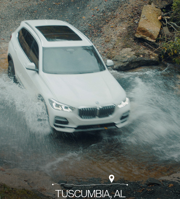 White BMW SUV driving through a body of water with "Tuscumbia, AL" at the bottom